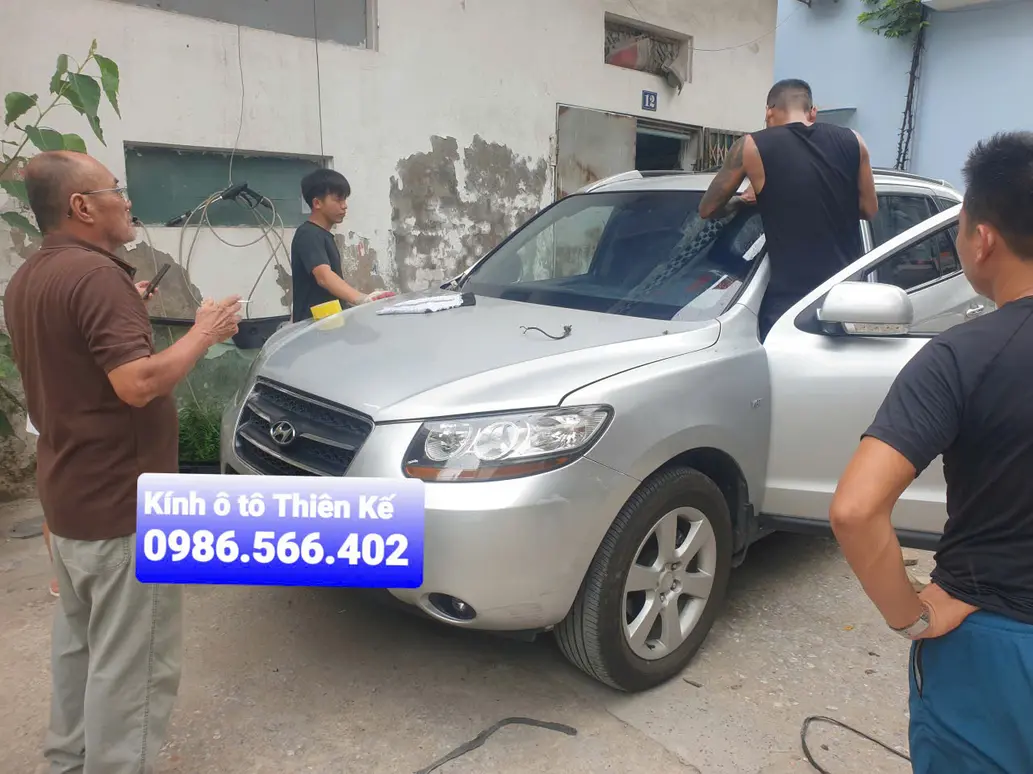 Technician inspecting Pilkington AGC Fuyao glass post-installation at Thiên Kế workshop with focus on ADAS calibration